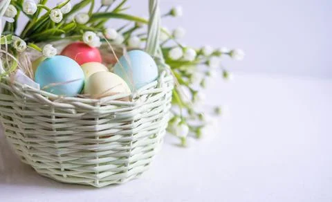 Baskets with Easter colored eggs on a white wooden table surrounded by delicate Foto stock