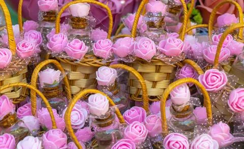 Baskets filled with decorative bottles and pink flowers arranged for sale a.. Stock Photos
