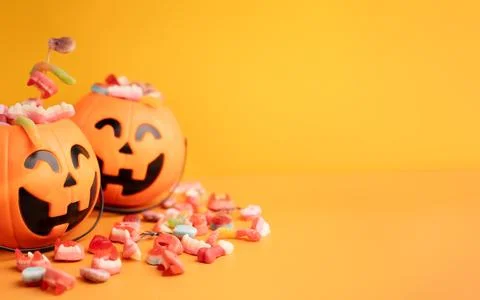 Baskets in the form of pumpkins with sweets on yellow background Stock Photos