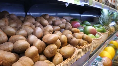 Baskets of kiwi, mango, pineapple and other fruits on a store shelf. Stock Footage 303369286