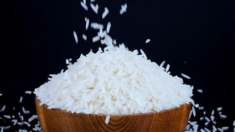 Basmati white rice falling in wooden bowl on a black spinning background Video stock 261064355