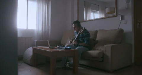 Bass player practicing his instrument with headphones and a computer Stock Footage 291027420