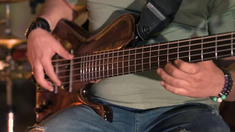 Bassguitar player playing slowly e-bass bracelets | 4K Stock Footage 157811902