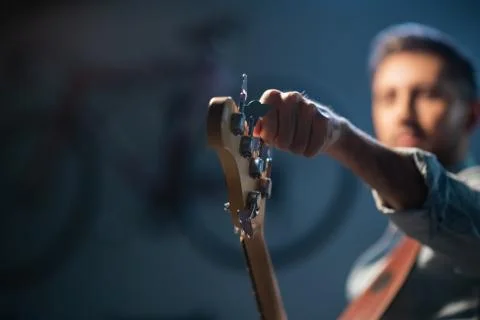 The bassist adjusts the electric bass guitar, in the foreground of the pegs and Stock Photos