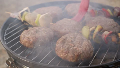Basting meat patties and vegetable skewers with oil on grill Stock Footage 261462985