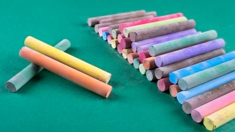 Batch of colored chalk arranged on green background Stock Photos