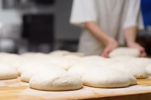A batch of formed dough pieces on a table in the kitchen of a local bakery re Stock Photos
