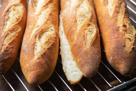 Batch of freshly baked baguettes background, whole and cutted baguettes. Stock Photos