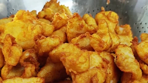 Batch of golden crispy fried fish pieces in a stainless steel colander. Stock Footage 342739387