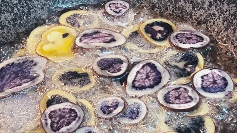 Batch of sliced native Peruvian purple potatoes frying in hot bubbling oil. 動画素材 339078412