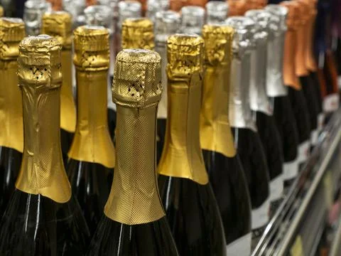 The batch of sparkling wine  bottles stand in a row on the wine store shelf. Stock Photos