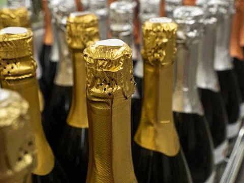 The batch of sparkling wine  bottles stand in a row on the wine store shelf. Stock Photos