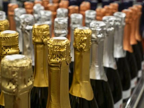 The batch of sparkling wine bottles stand in a row on the wine store shelf. Stock Photos