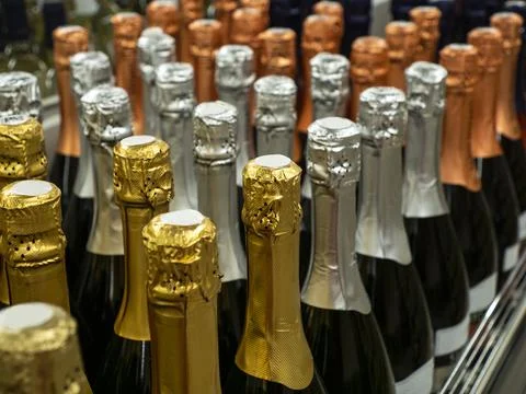 The batch of sparkling wine  bottles stand in a row on the wine store shelf. Stock Photos