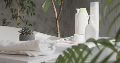 Bath accessories in a clean, white modern bathroom, surrounded by plants. Stock Footage 260500673
