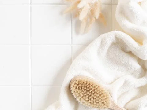 Bath background flat lay with white towels, wood brush and dry flowers on whi Stock Photos