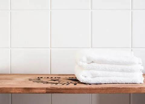 Bath background front view with white towels on brown wood shelf and wall til Stock Photos