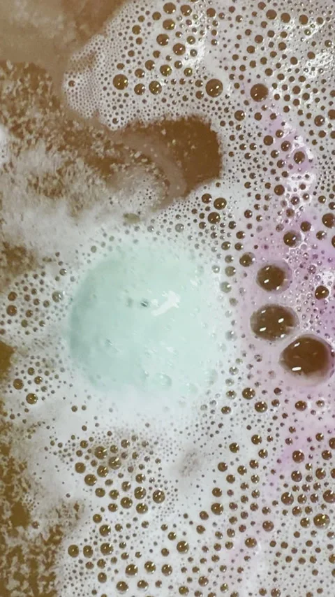 Bath bomb rotates and fizzes bubbles in bathtub water. Stock Footage 334762987