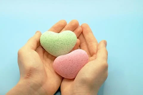 Bath bombs in the shape of a heart close-up in the hands. Stock Photos