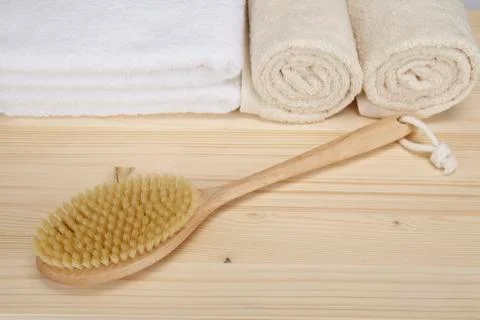 Bath brush and towels on a tabletop of spruce wood Stock Photos