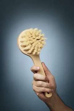 Bath Brush Man holding a brush made of wood and natural fibers in his hand... Stock Photos