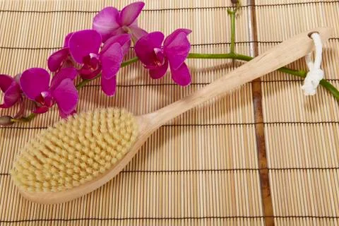 Bath brush on a mat of bamboo and an orchid Stock Photos