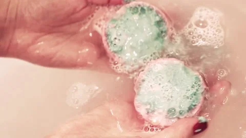 Bath salt ball dissolves in the hands. Bubbles like two eyes on the face Stock Footage 149519421