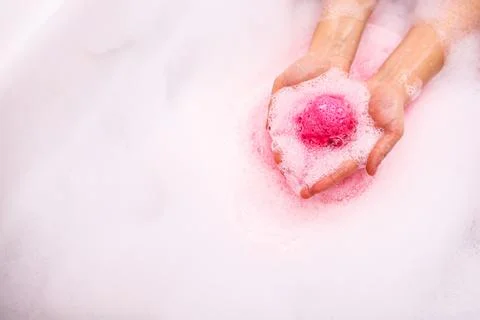 Bath salt ball dissolves in the hands. Colored bath bomb Stock Photos
