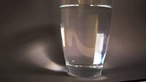 Bath salt form tablet drop slow motion in vase with decomposition reaction water Stock Footage 114749757