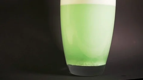 Bath salt green dissolves in vase of water in slow mo with particle drilling Stock Footage 119542322