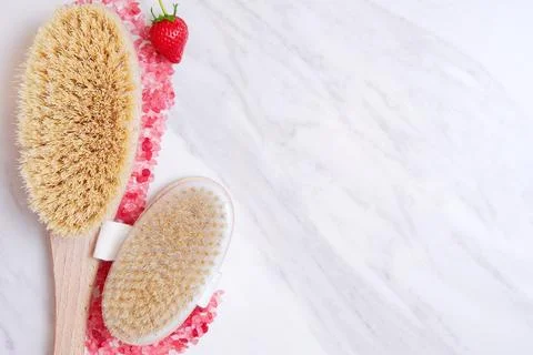 Bath scrub brush bordered with pink mineral sea salt grain and sweet strawberry Stock Photos