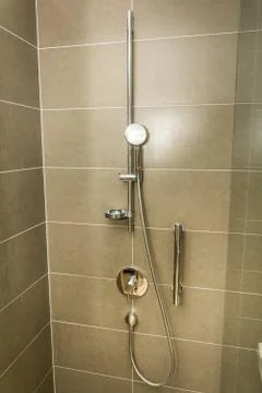 Bath shower on the brown tile wall Stock Photos