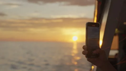 Bathed in the warm glow of a sunset, uses her smartphone to capture the Vidéo 257100005