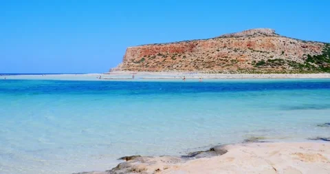 Bathers stroll through beautiful crystal clear waters beach with yellow sand  Video stock 244854327