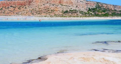 Bathers stroll through beautiful crystal clear waters beach with yellow sand  Video stock 244854514