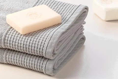 Bathroom accessories. Stack of gray soft towels and two bars of soap on a gray Stock Photos