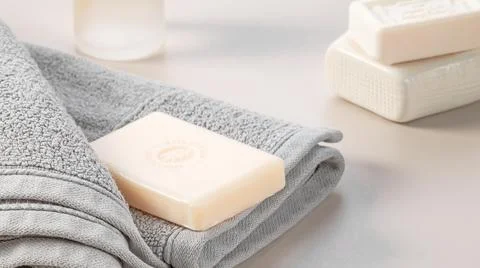 Bathroom accessories. Stack of gray soft towels and two bars of soap on a gray Stock Photos