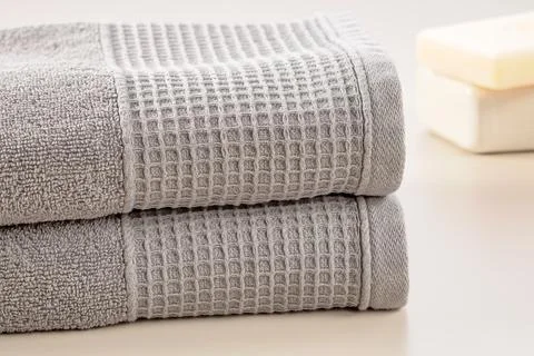 Bathroom accessories. Stack of gray soft towels and bar of soap on a gray b.. Stock Photos