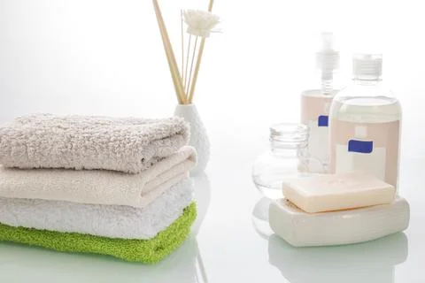 Bathroom accessories. Stack of soft towels, soap and perfume bottles on a mirror Stock Photos