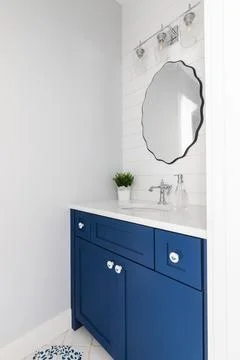 A bathroom with a blue cabinet and pattern tiles. Stock Photos