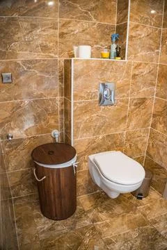 Bathroom with brown tile wall trim, bamboo basket and white toilet Stock Photos