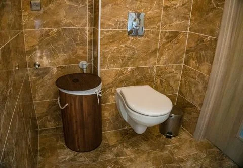 Bathroom with brown tile wall trim, bamboo basket and white toilet Stock Photos