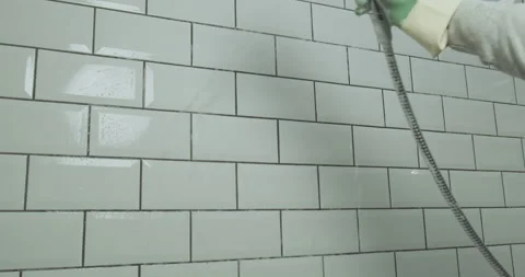 Bathroom cleaning. The shower jet washes detergent off the white tiled wall Stock Footage 229923946