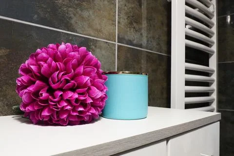 Bathroom decor elements. A blue jar of cream and a pink bright artificial d.. Fotos de archivo