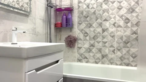 The bathroom is decorated in gray and white tones, which contains a white Stock Footage 269431995