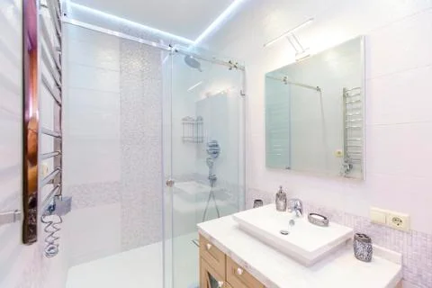 Bathroom with elegant rectangular washbasin, toilet and shower. Mirror with l Stock Photos