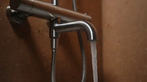 Bathroom faucet, bath mixer made of brushed steel. Human hand turns on tap Stock Footage 327292500