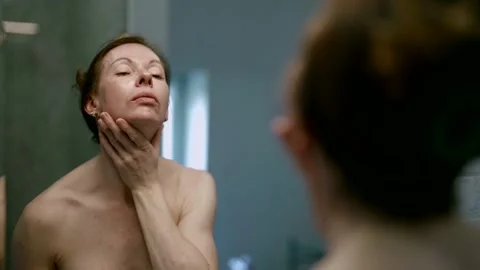 In the bathroom, in front of the mirror, a middle-aged adult woman pays Video stock 274303400