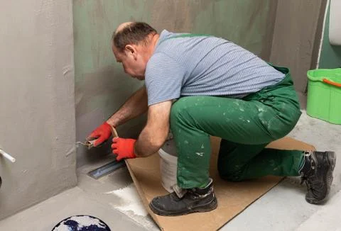 In the bathroom, a general construction worker applies moisture insulation using Foto stock