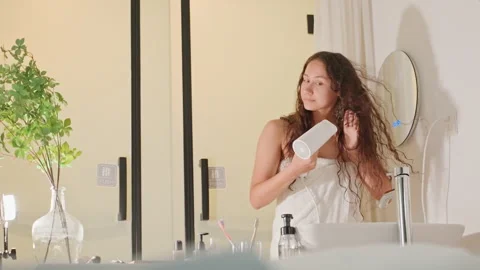 Bathroom hair styling. Creator showcases relaxed hair tutorial in hotel bathroom 動画素材 334625341